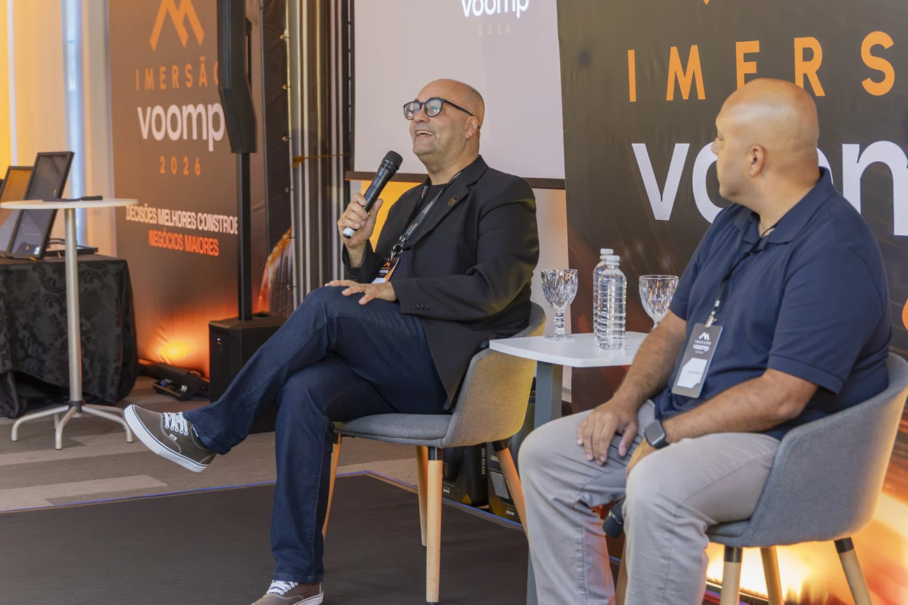 Isaac Martins com microfone participando de conversa sobre negócios em um palco de evento